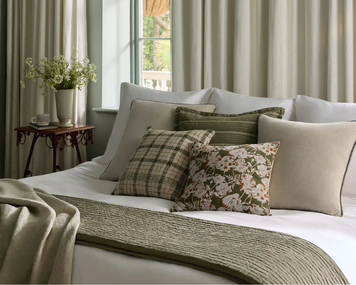 Neatly made bed with decorative pillows in a bedroom setting.
